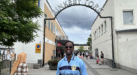 leende man framför skylten "Rinkeby Torg"