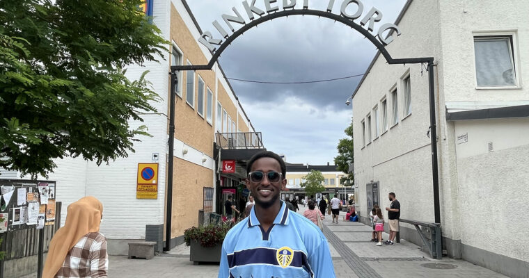 leende man framför skylten "Rinkeby Torg"