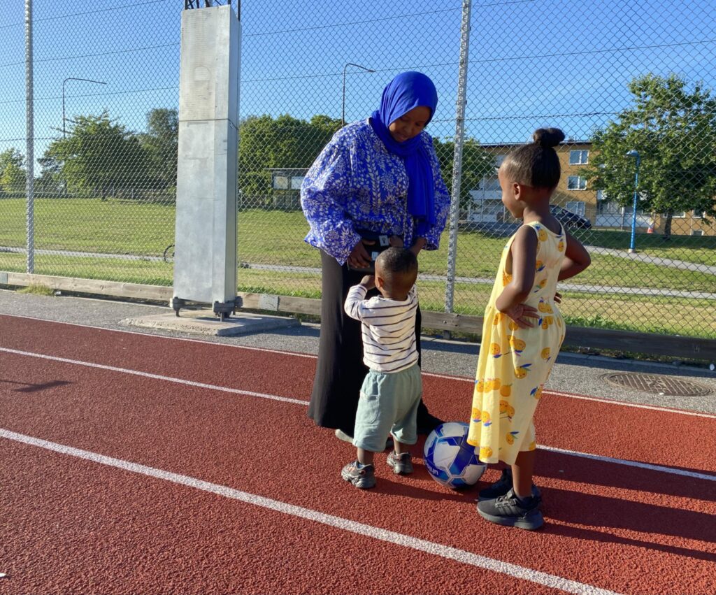 En kvinna och två barn med en fotboll