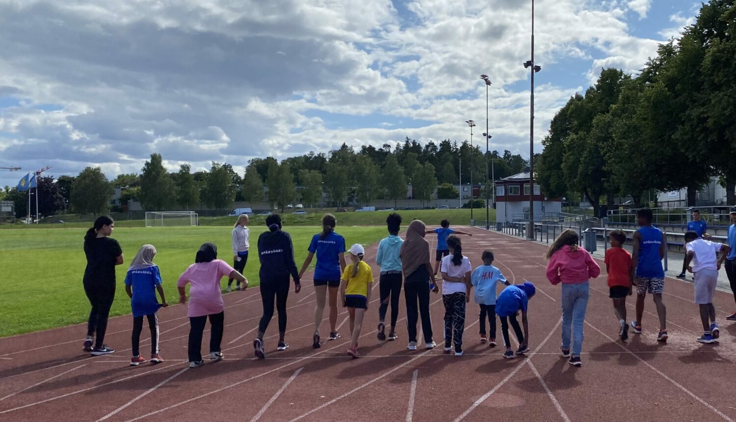 En grupp barn som springer på en löparbana utomhus