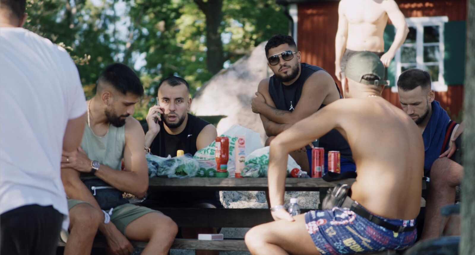 Rinkeby United fotbollslaget som sitter vid ett bord en sommardag.