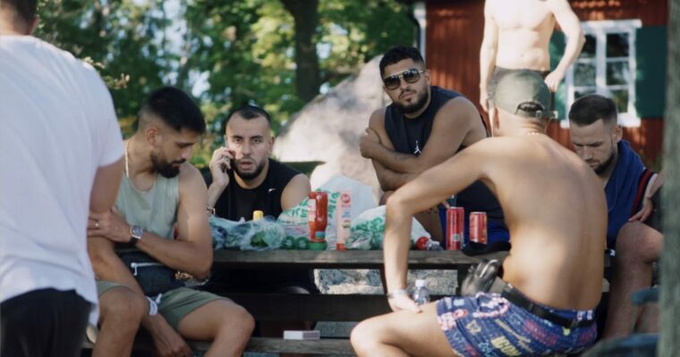 Rinkeby United fotbollslaget som sitter vid ett bord en sommardag.