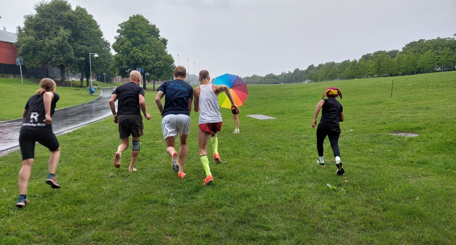 Fem löpare fotade bakifrån springer i regnet.