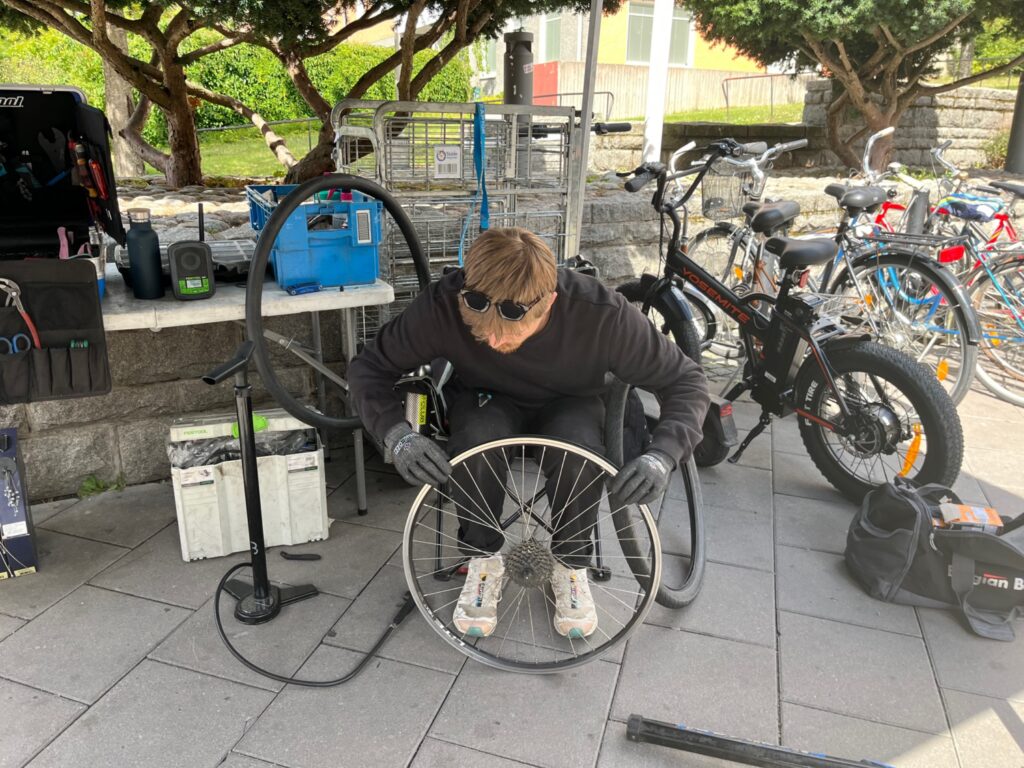 En kille som sitter och lagar en cykel.