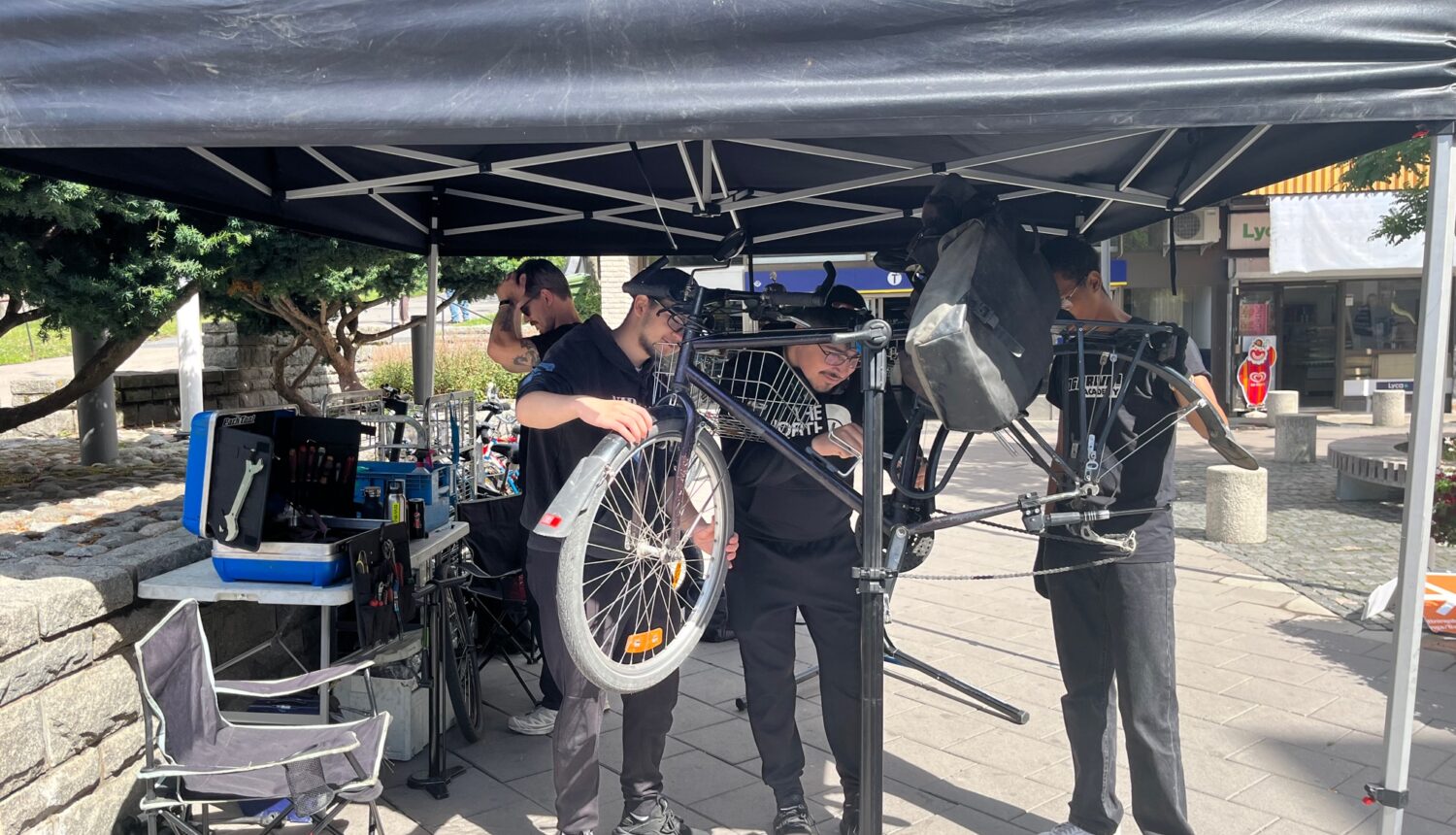 Killar som mekar med en cykel på torget i Hjulsta.