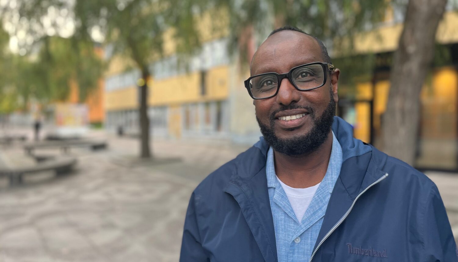 Leende svensk-somalisk man i glasögon.