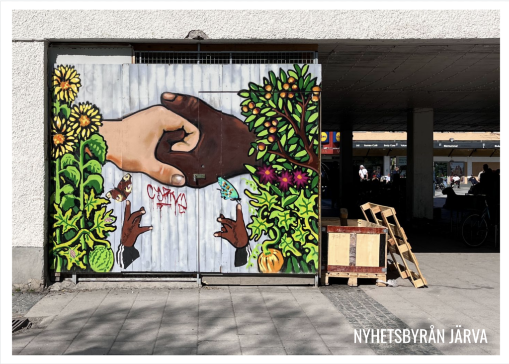En väggmålning i Rinkeby, två händer möts.