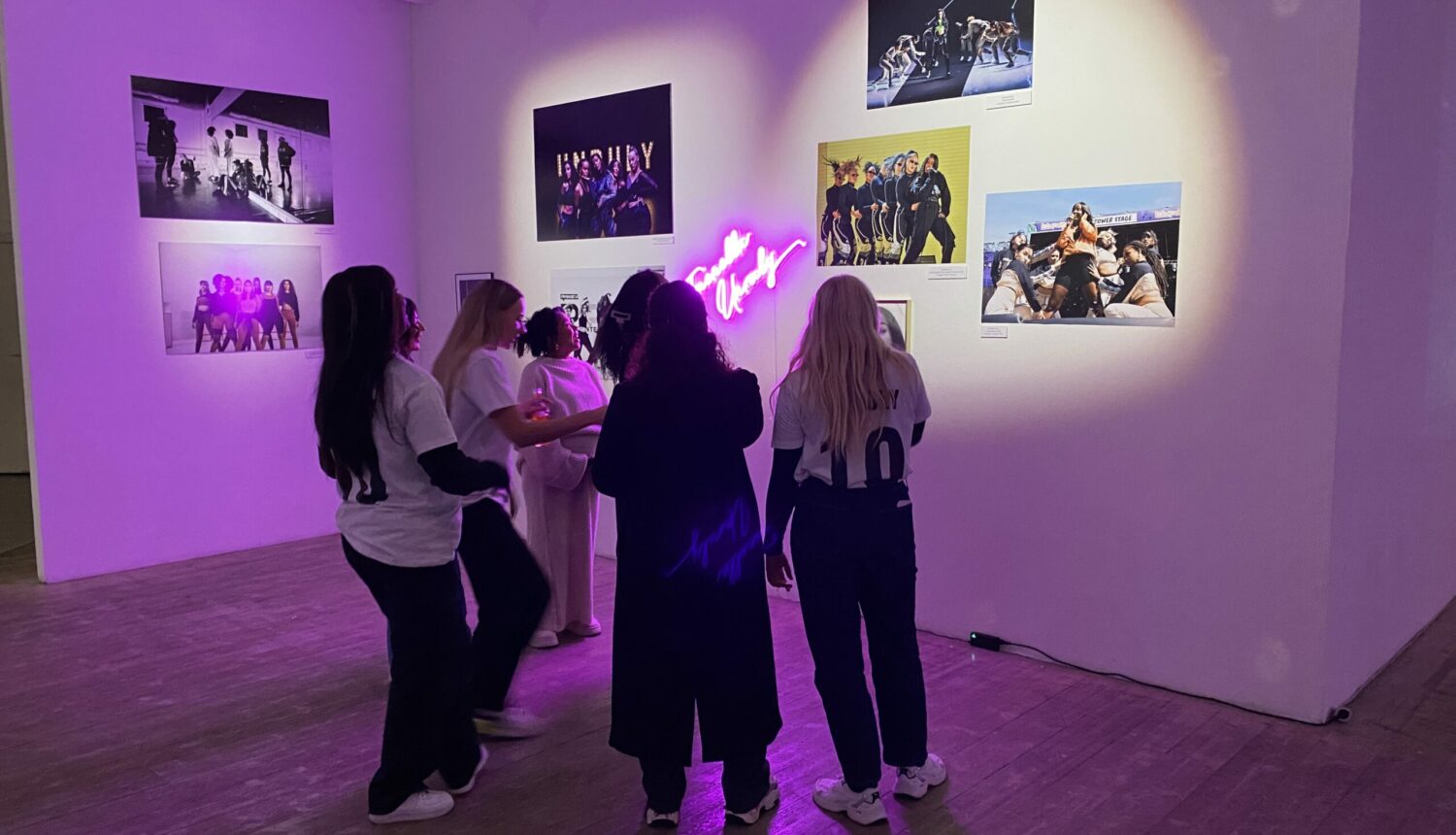 Några tjejer som står och tittar på foton på ett galleri