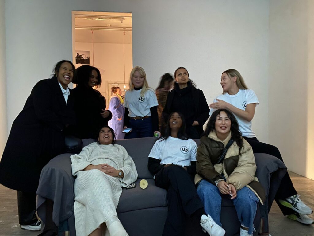 En grupp tjejer sitter och står runt en soffa