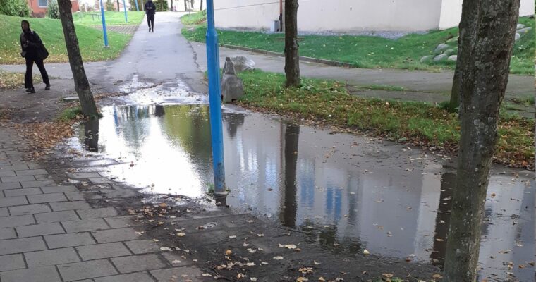 En stor vattenpöl på en trottoar.