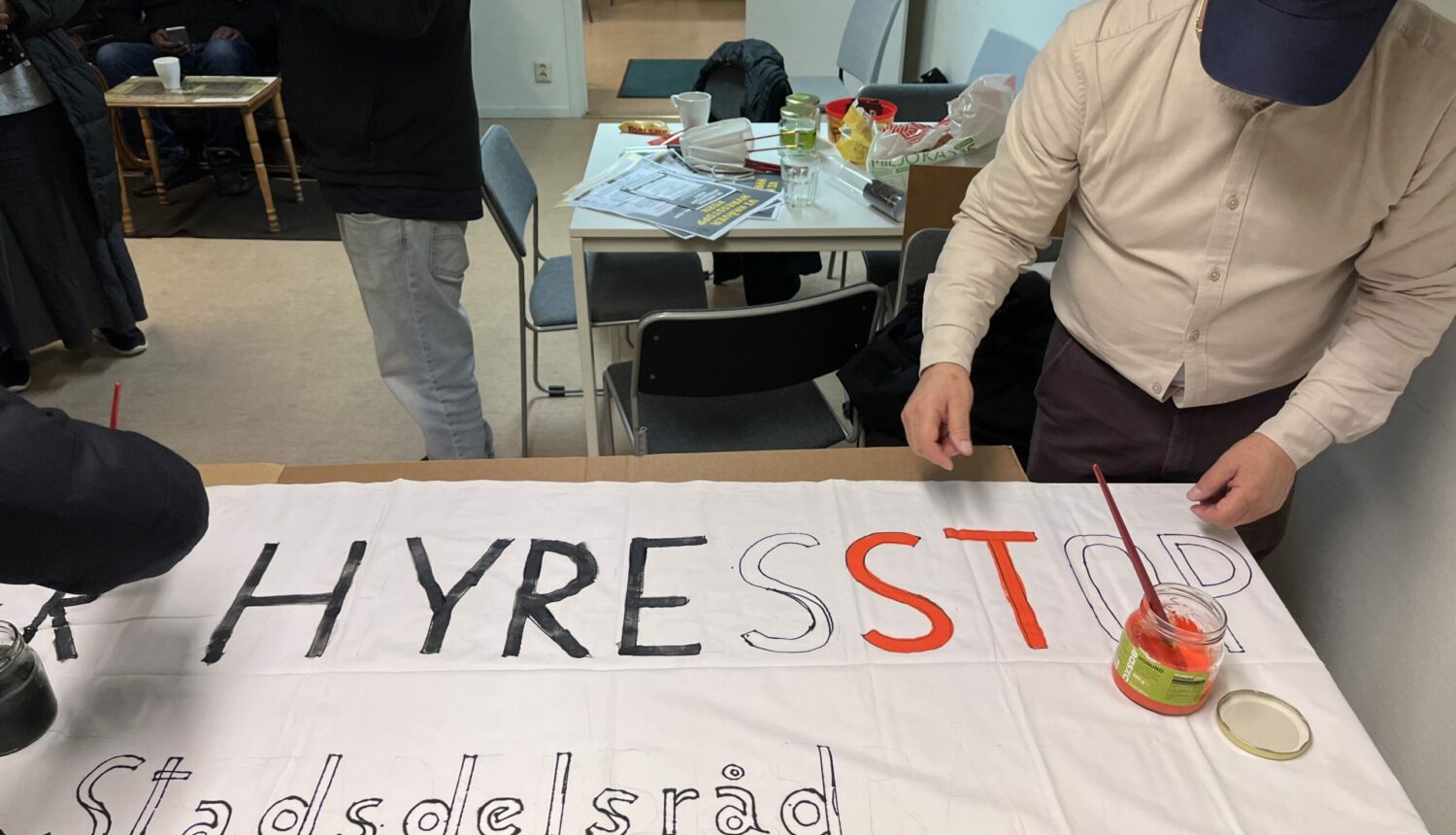En man målar en banderoll med ordet Hyresstopp.