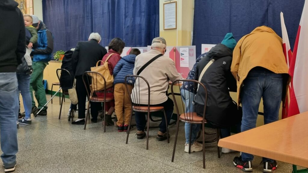 Vallokal i Polen, folk sitter vid samma bord.