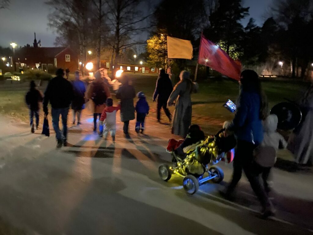 Fackeltåg med en barnvagn med ljusslinga i förgrunden