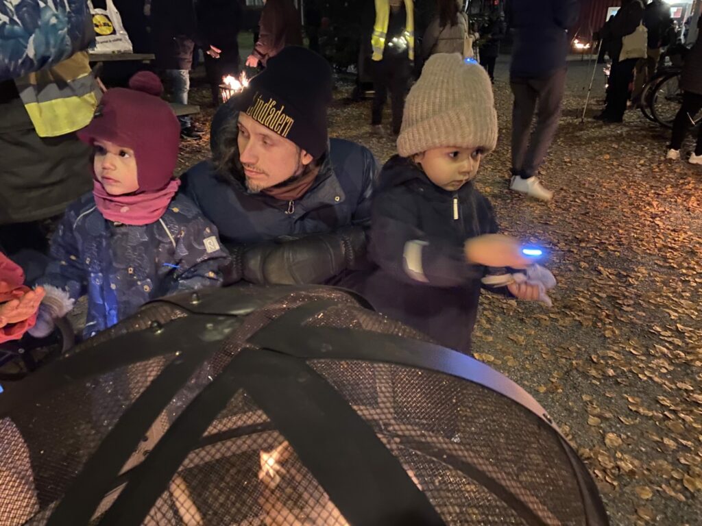 En man och två små barn värmer sig vid en eld