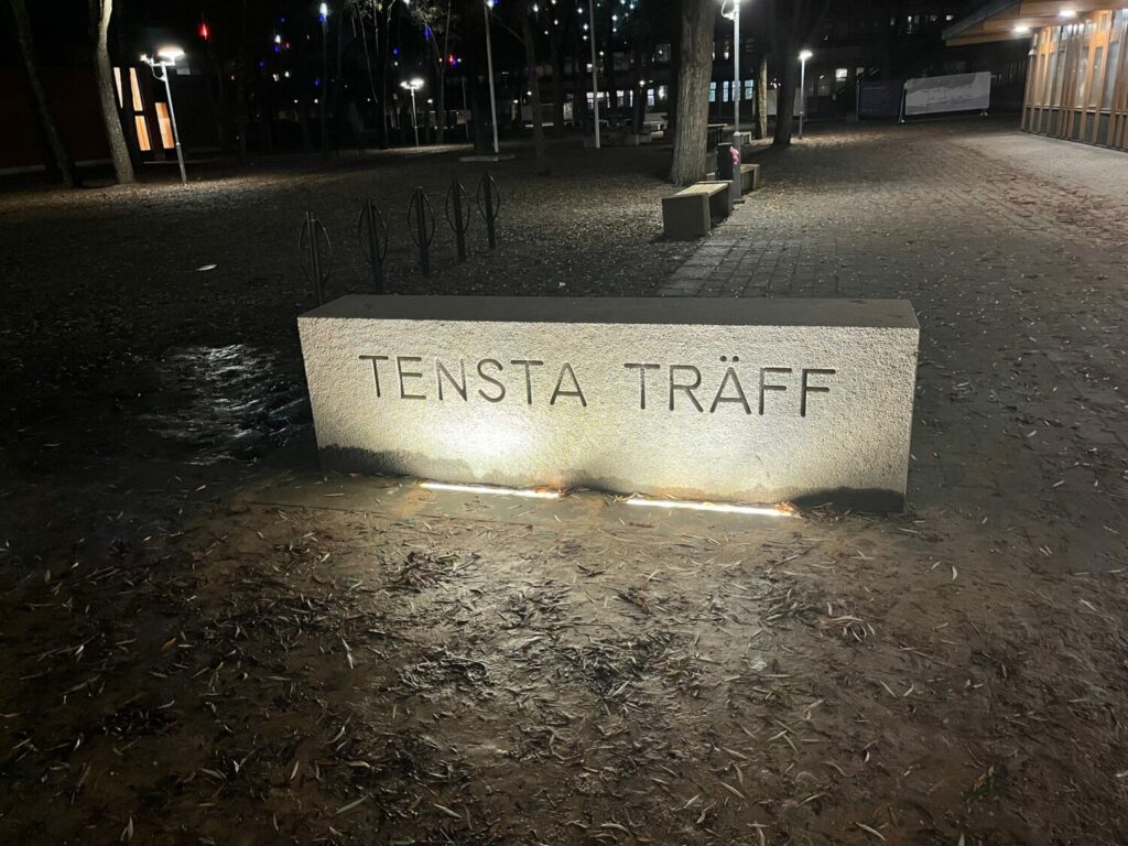 Skylten för Tensta Träff i mörker.