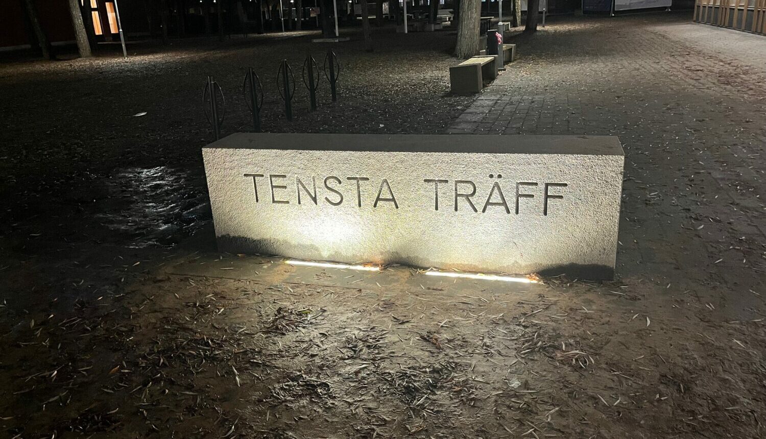 Skylten för Tensta Träff i mörker.