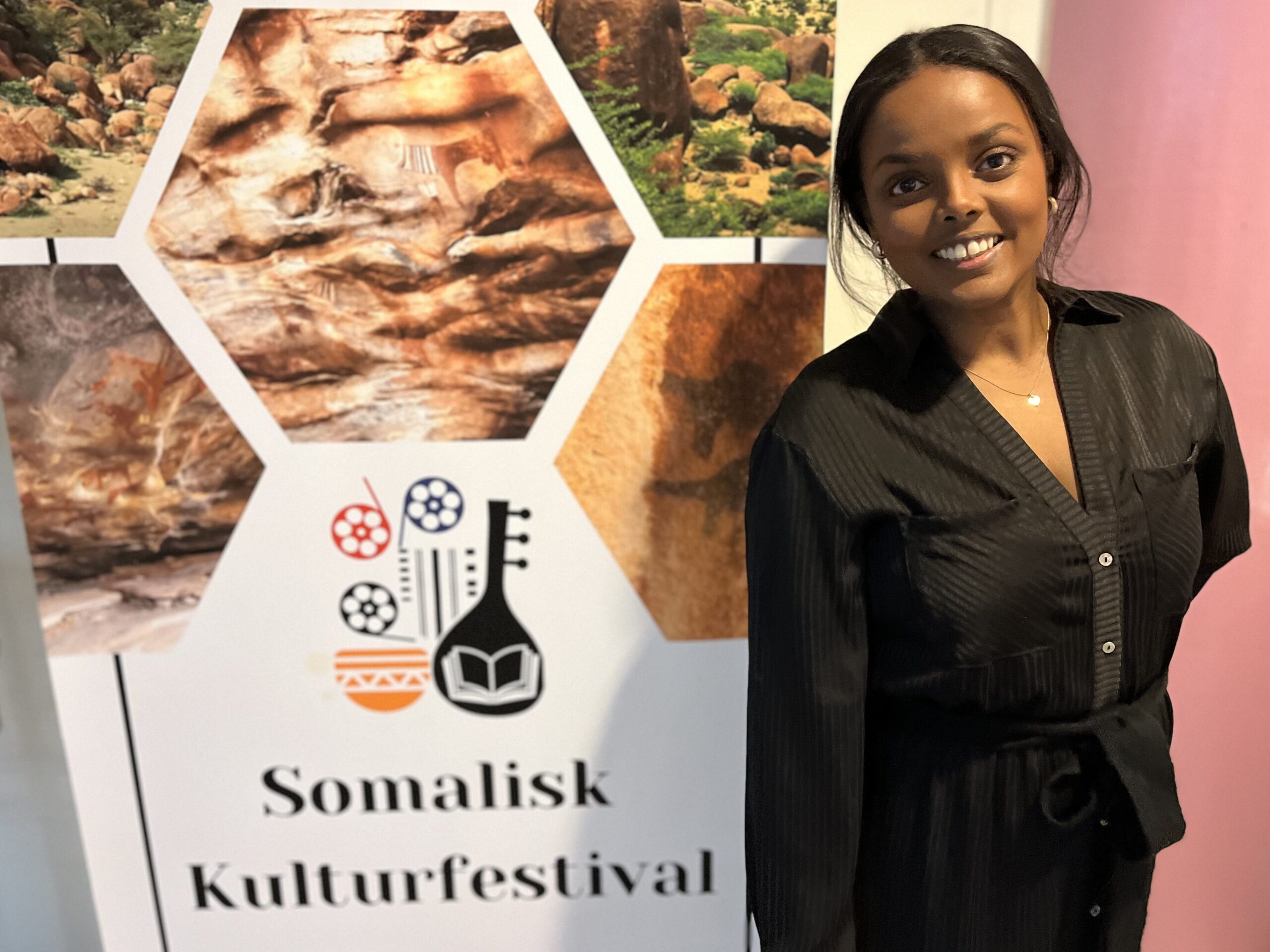 kvinn klädd i svart står framför roll up med texten Somalisk kulturfestival