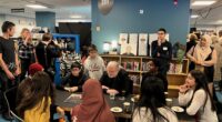 Jon Fosse sitter och pratar med eleverna runt ett bord i Rinkeby bibliotek.