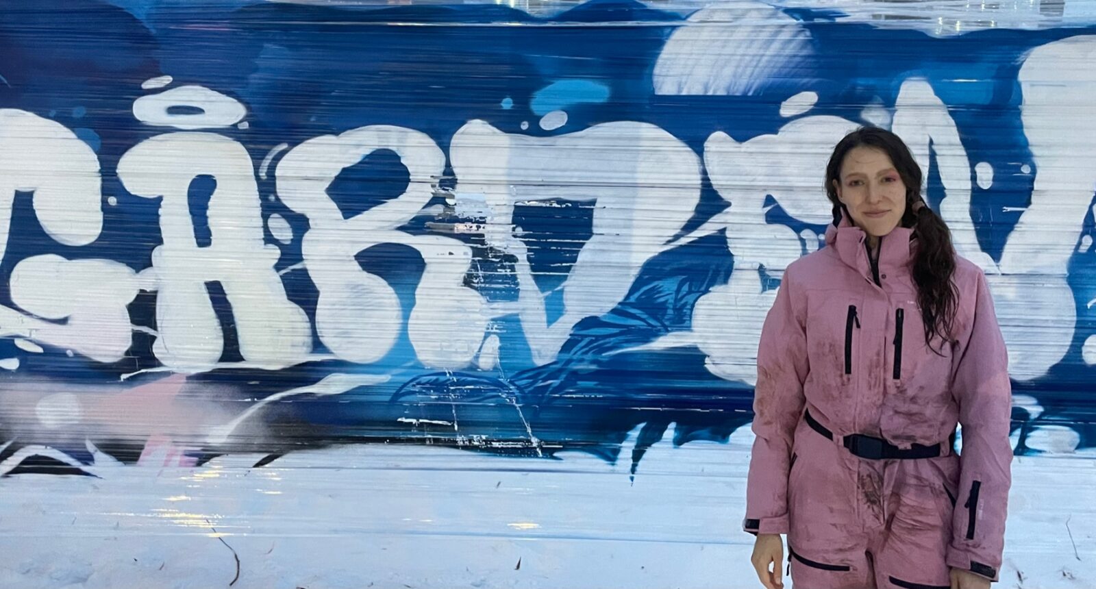 Kvinna framför graffitimålning med texten Gården.