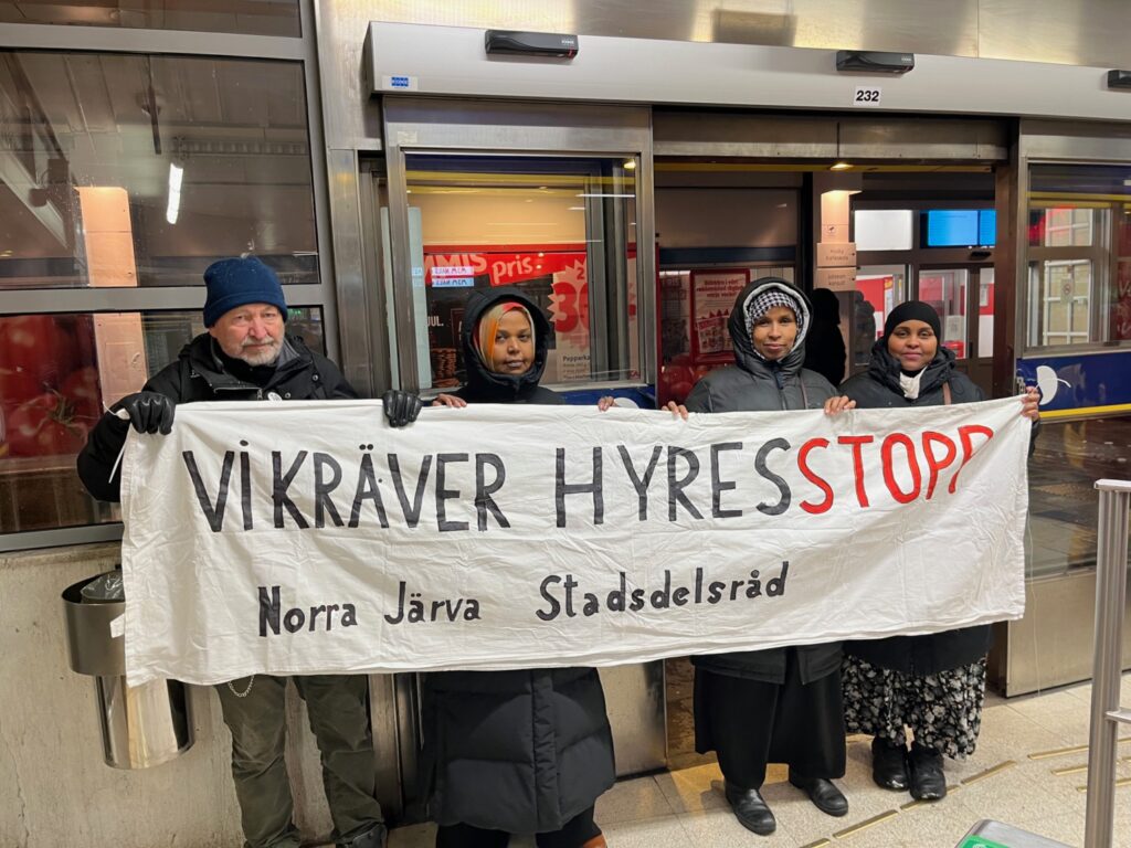 Fyra personer håller i en banderoll med krav om hyresstopp.