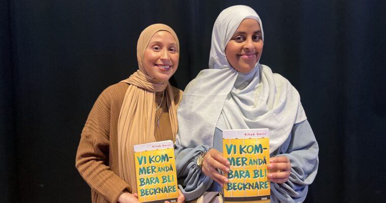 Två kvinnor ler in i kameran och håller i varsin bok