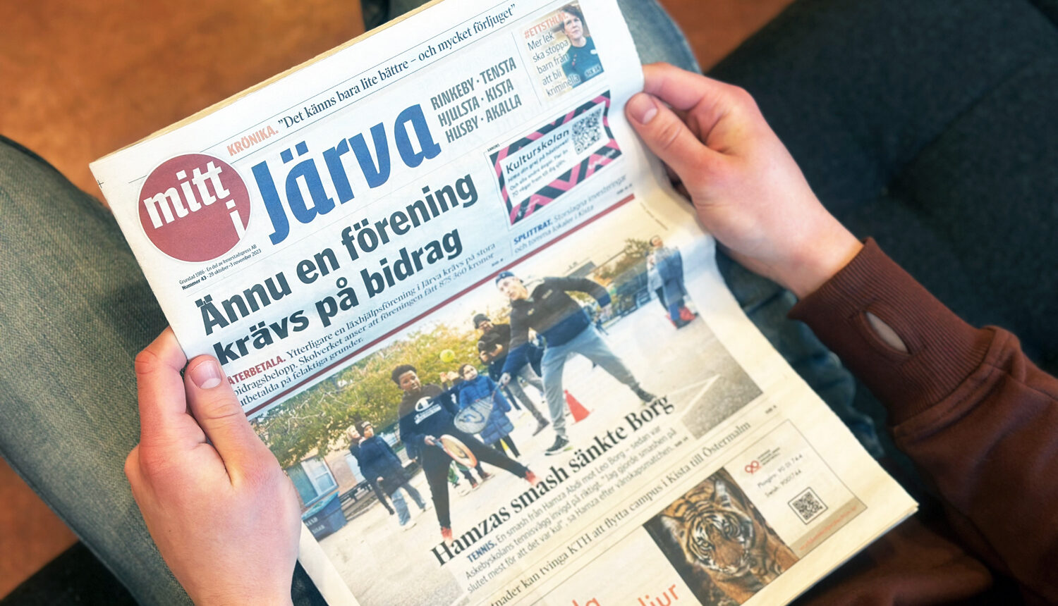 Händer som håller i tidningen mitt i Järva