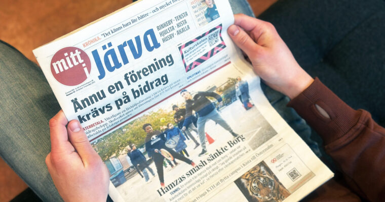 Händer som håller i tidningen mitt i Järva