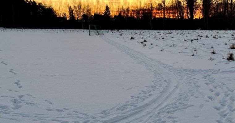 skidspår i snön mot en gryningshimmel i varma färger