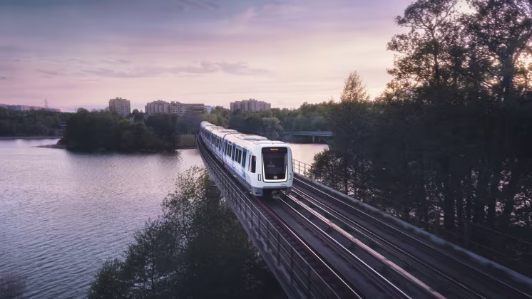Ett modern tunnelbanetåg åker på en bro med vatten under
