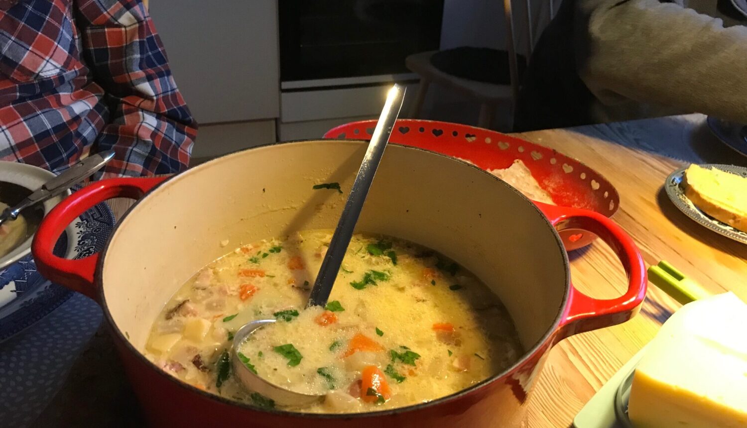 En gryta med soppa på ett matbord, med soppslev i.