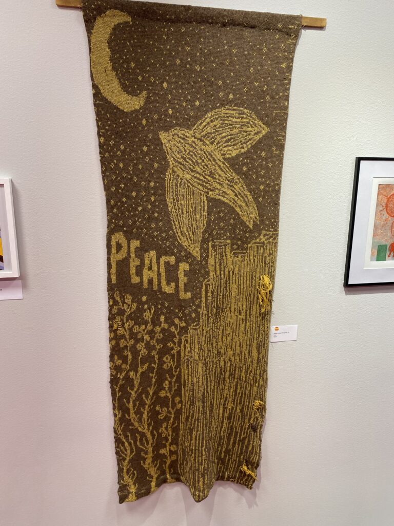 Stickat konstverk med ordet PEACE