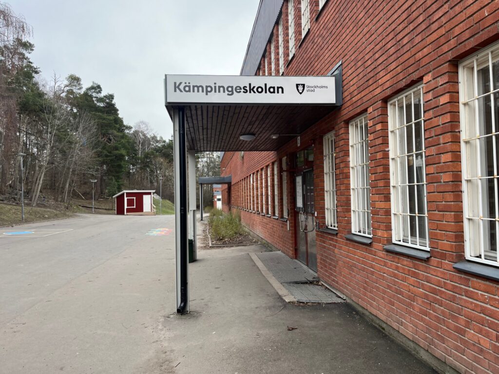 Röd tegelbyggnad, en skylt ovanför ingången med texten Kämpingeskolan.