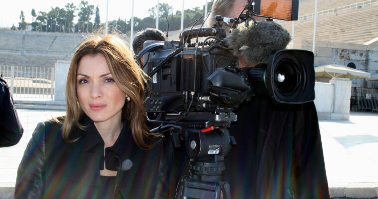 kvinna i svarta kläder tittar in i kameran bredvid en filmkamera