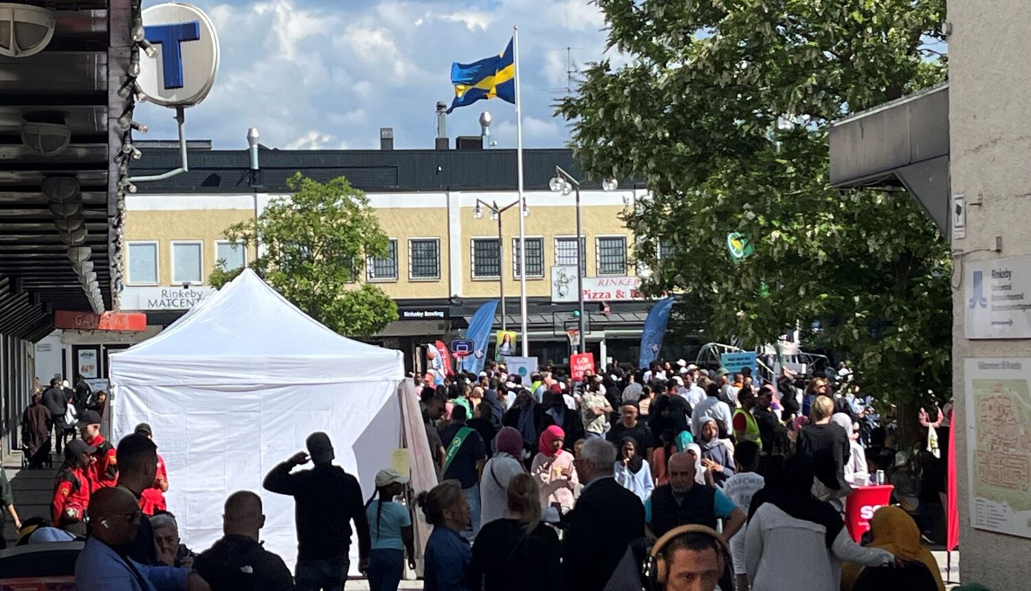 torg med vimmel av människor, partytält och en hissad svensk flagga