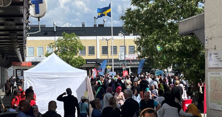 torg med vimmel av människor, partytält och en hissad svensk flagga