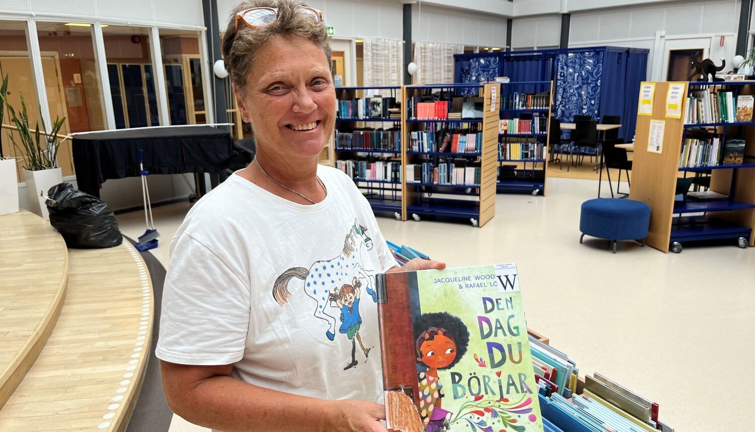 kvinnlig skolbibliotekarie står och håller i en bok