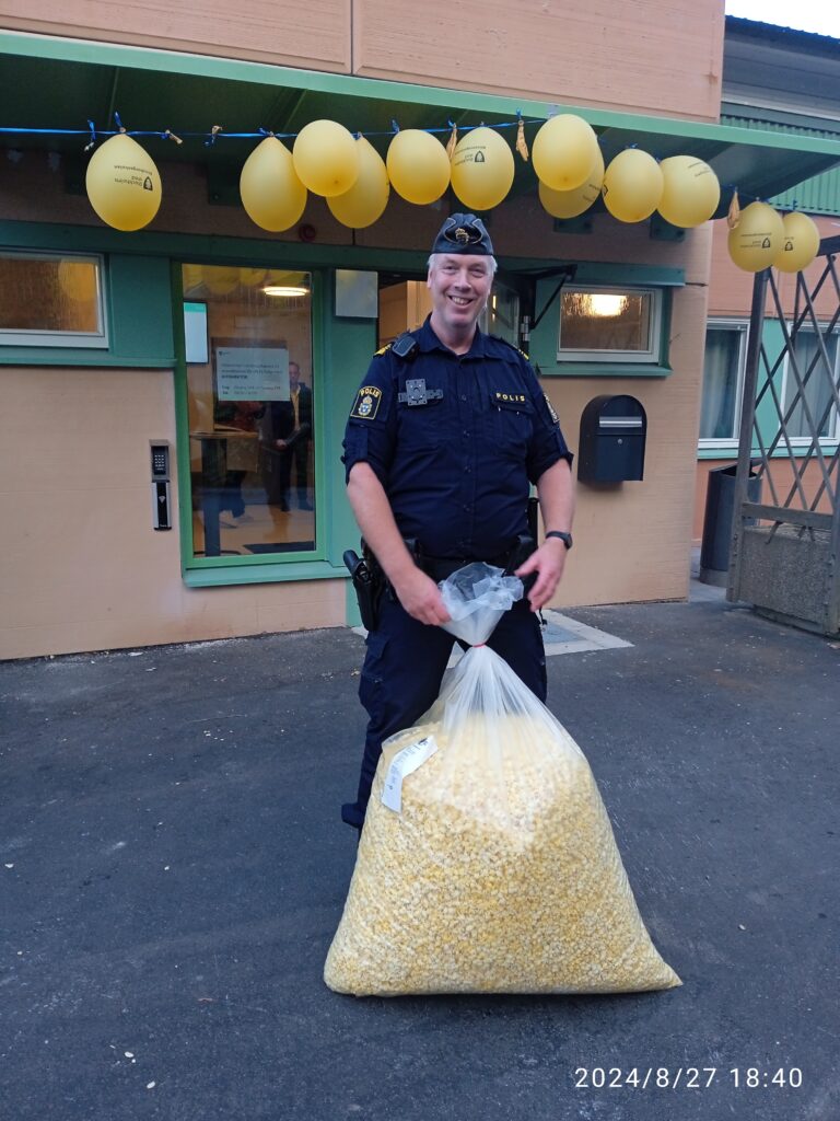 En polis i uniform håller en stor plastsäck med popcorn.