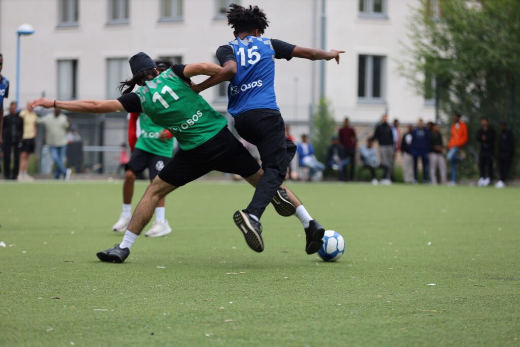 två fotbollsspelare i närkamp på konstgräsplan