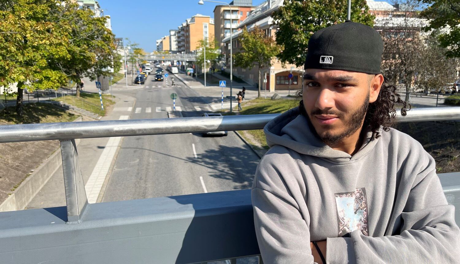 man står med armarna i kors på en bro över Rinkebystråket och tittar in i kameran