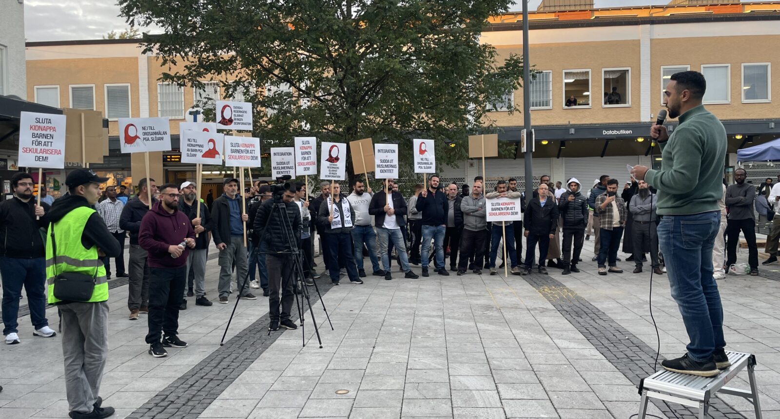 demonstranter med skyltar emot slöjförbud på ett torg