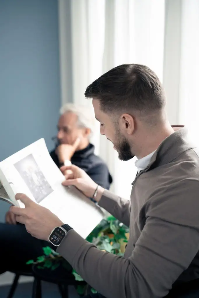 To patienter slapper af i venteområdet. Den ene læser avis, mens den anden hviler sig.