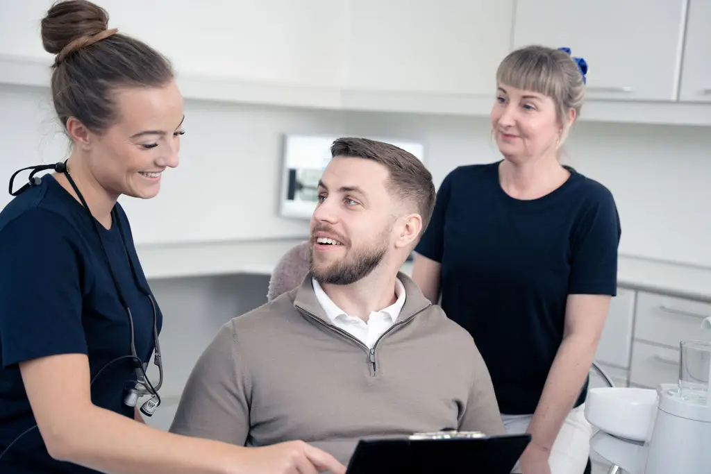 Mandlig patient i dialog med tandlæge og klinikpersonale i behandlingsrum hos Tandlægerne Ølandshus