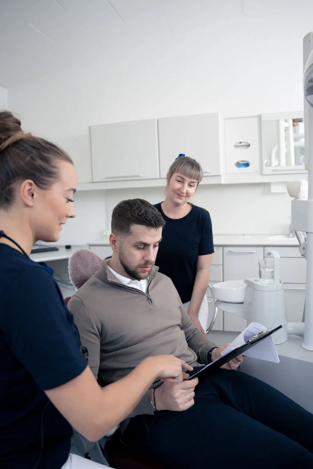 Mandlig patient læser information sammen med klinikpersonale hos tandlæge på Amager