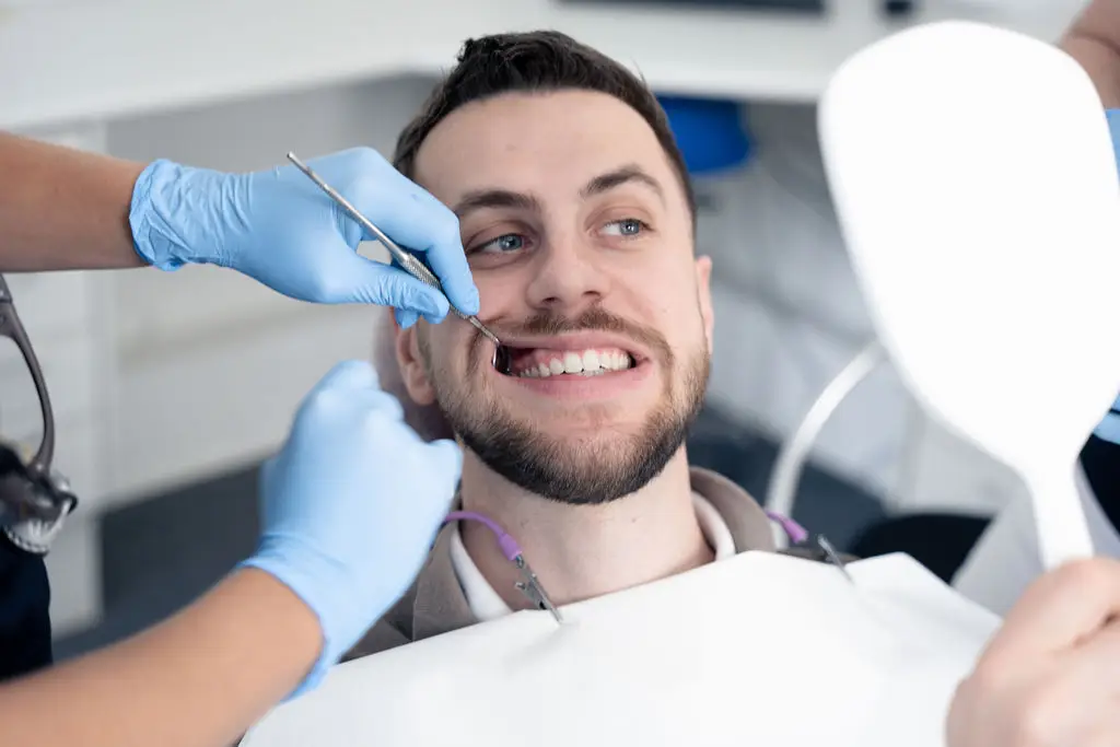 Patient inspicerer tænder i spejl under tandlægeundersøgelse hos Tandlægerne Ølandshus