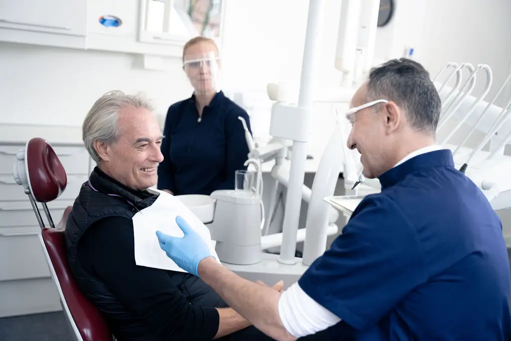 Tandlæge taler med smilende patient før behandling hos Tandlægerne Ølandshus