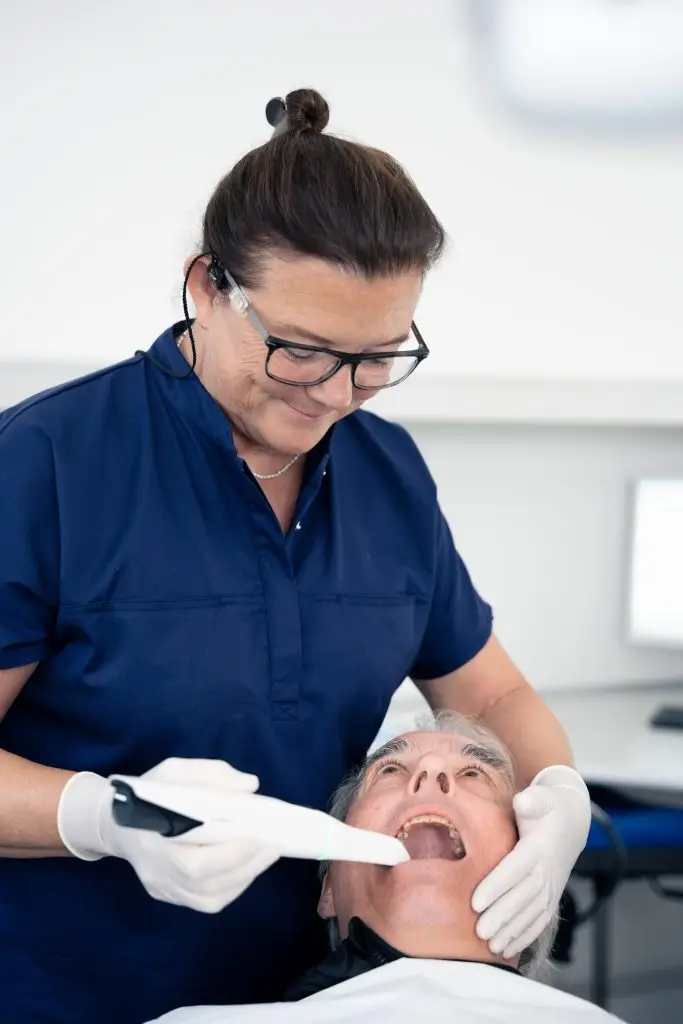 Klinikassistent udfører scanning eller undersøgelse af ældre patient i tandklinik på Amager