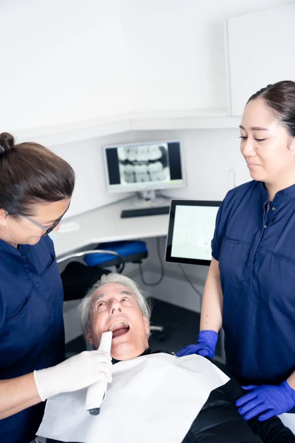 Patient til undersøgelse hos tandlæge og klinikassistent hos tandlægerne Ølandshus på Amager. Røntgenbilleder ses i baggrunden.