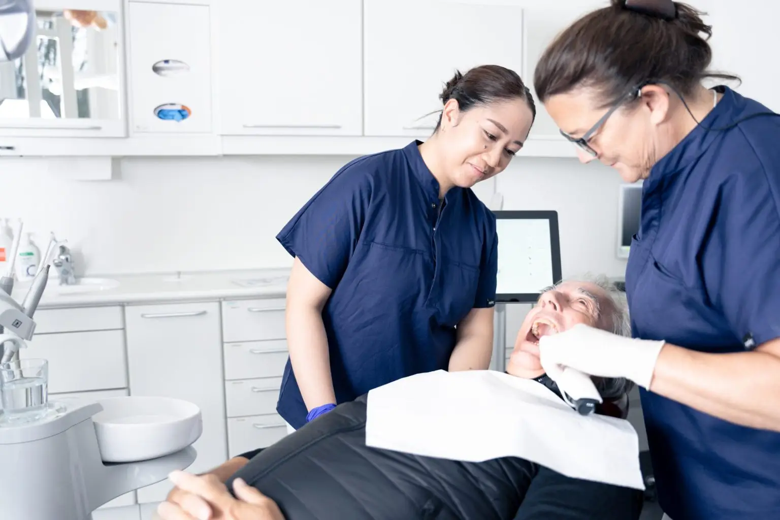 To tandlæger undersøger ældre patient i behandlingsrum hos Tandlægerne Ølandshus