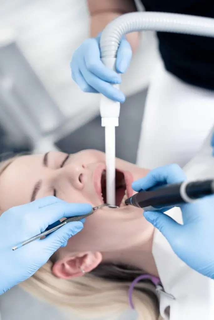 Tandlæge udfører tandrensning med sug og instrument hos patient på Amager