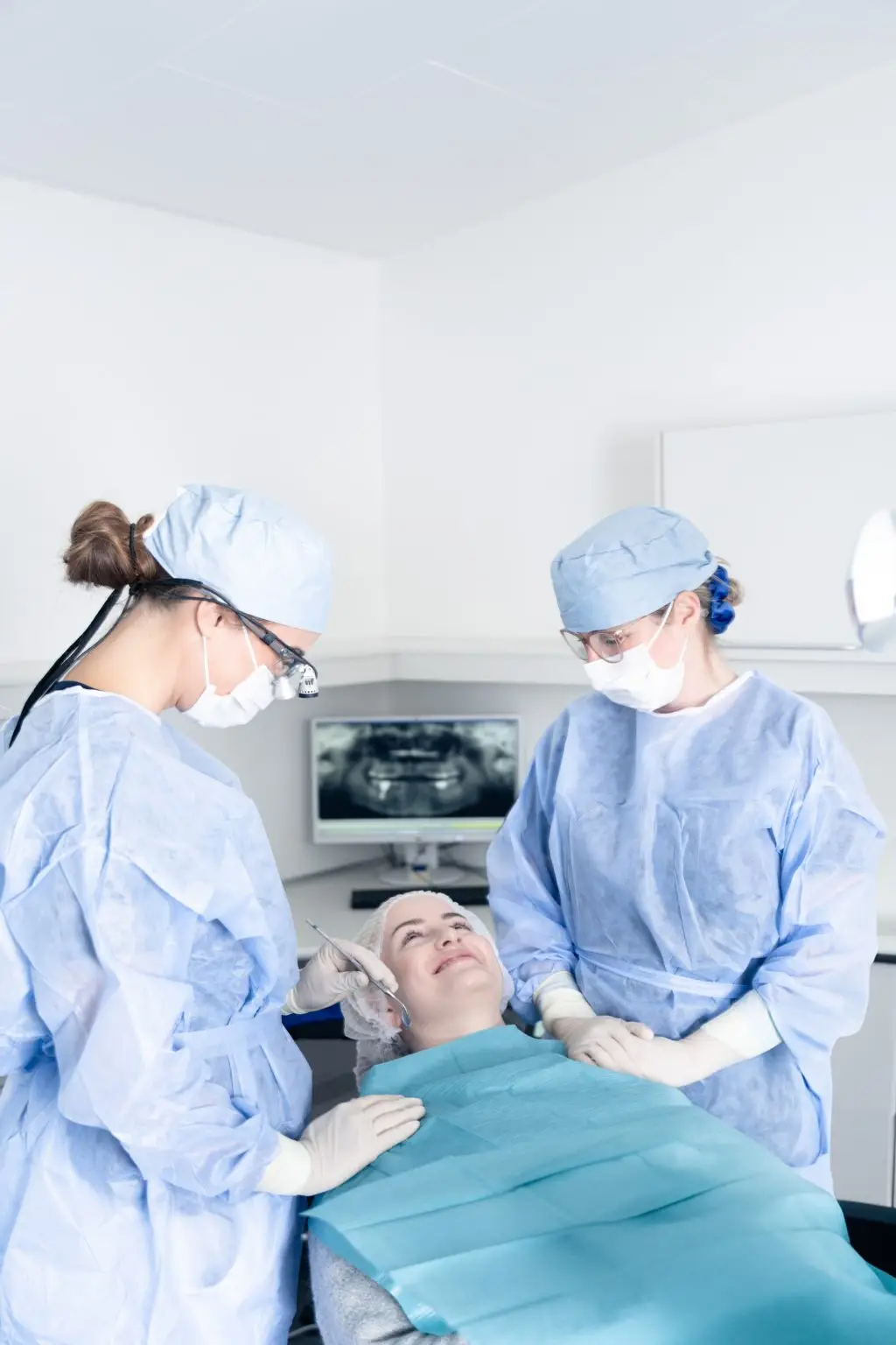 Patient modtager kirurgisk behandling af tandlæger iført sterile dragter hos Tandlægerne Ølandshus